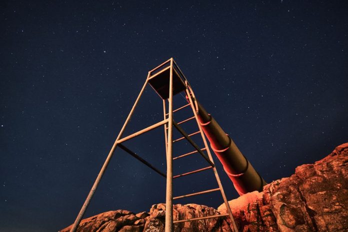 Telescopio apuntando al cielo nocturno estrellado durante observación astronómica