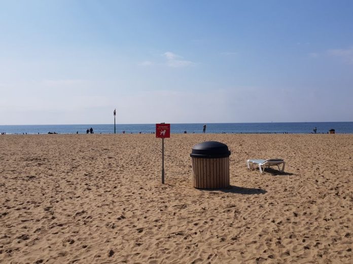 Contenedor de reciclaje de vidrio en entorno costero durante el verano