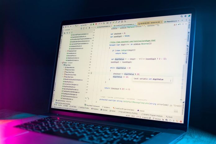 Desarrollador trabajando en un ordenador portátil con código en pantalla