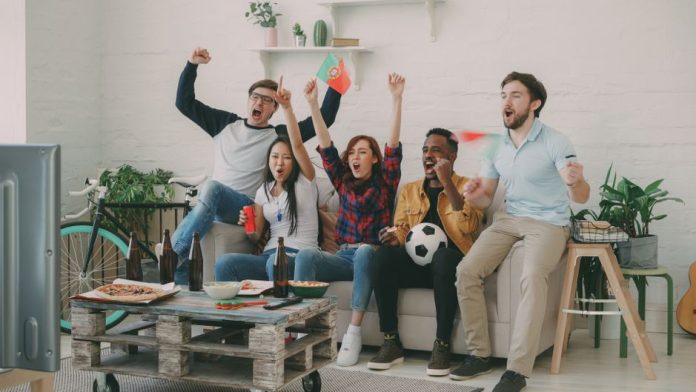 Familia reunida viendo fútbol en el salón de casa compartiendo momentos juntos