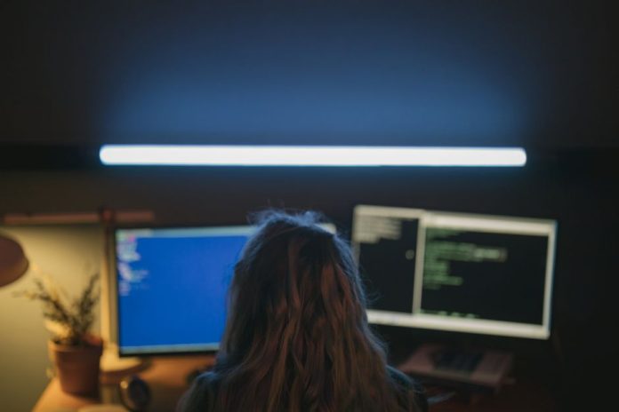 Joven desarrollador frente a una pantalla de ordenador en un espacio de trabajo nocturno