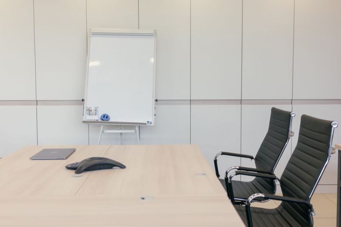 Sala de reuniones corporativa vacía con mesa de consejo