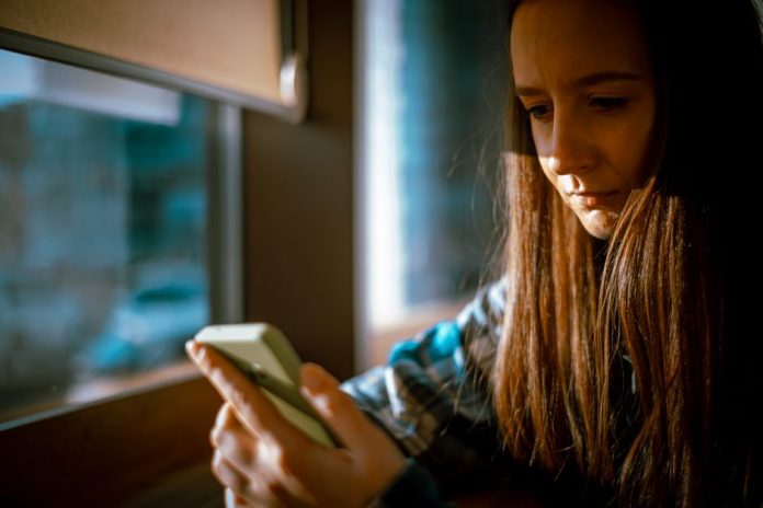 Adolescente usando smartphone bajo supervisión familiar en entorno doméstico