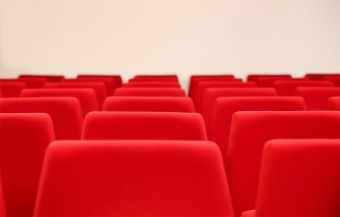 Interior de una sala de cine vacía con butacas y pantalla