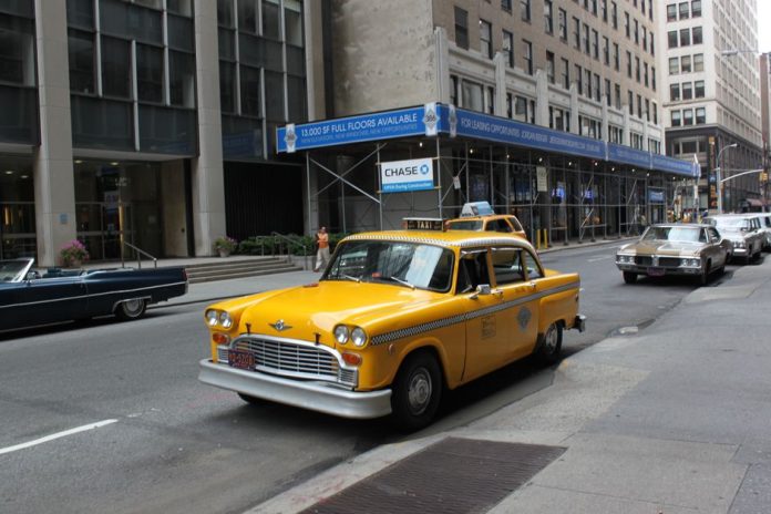 Taxi amarillo circulando por una calle urbana de Nueva York