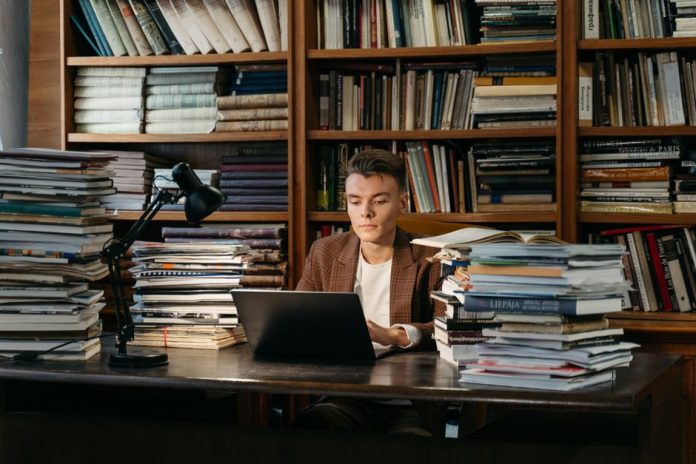 Escritorio de estudiante con libros abiertos en una biblioteca universitaria